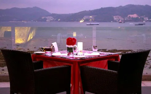 Dinner table set for two overlooking Andaman Sea at sunset, Phuket.