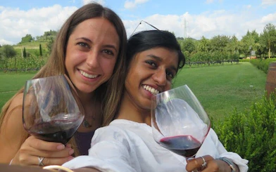 Two people enjoying wine in a vineyard during a Tuscany Tuk Tuk tour.