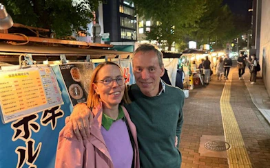 Couple enjoying Nakasu food stalls at night in Fukuoka during guided tour.