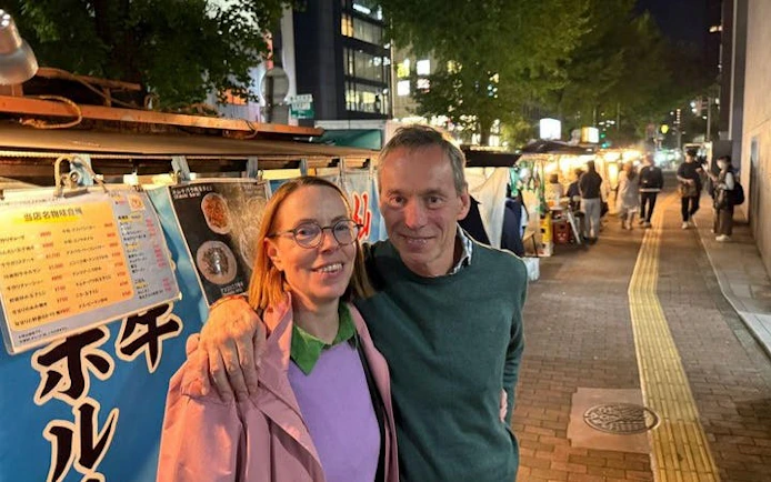 Couple enjoying Nakasu food stalls at night in Fukuoka during guided tour.
