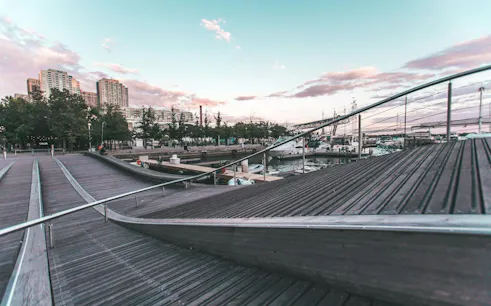 Toronto waterfront boardwalk with boats docked and city skyline in the background.