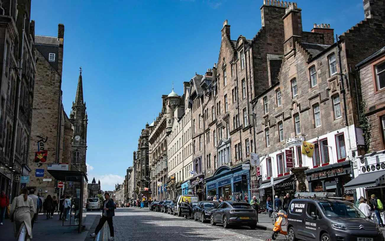 Edinburgh Old Town street view with historic buildings and people walking.