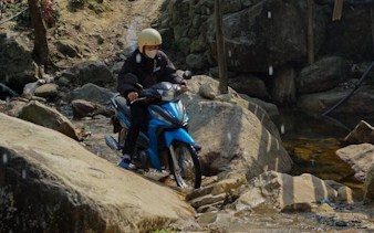 Motorbike crossing rocky stream in Sapa village tour, Vietnam.