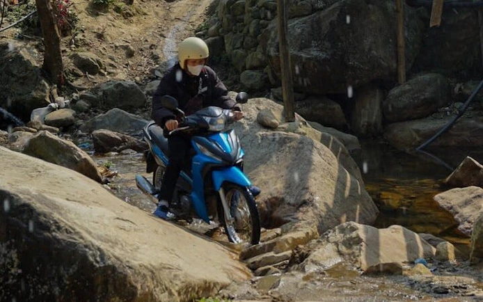 Motorbike crossing rocky stream in Sapa village tour, Vietnam.