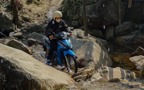 Motorbike crossing rocky stream in Sapa village tour, Vietnam.