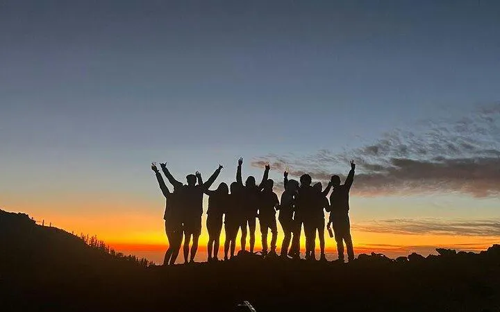 Group silhouetted against sunset at Teide National Park, Tenerife, during stargazing tour.