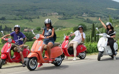 Tourists riding Vespas through Chianti vineyards in Tuscany.