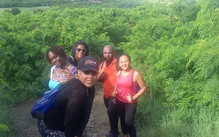 Group hiking through lush greenery on St. Maarten trail to island’s highest point.