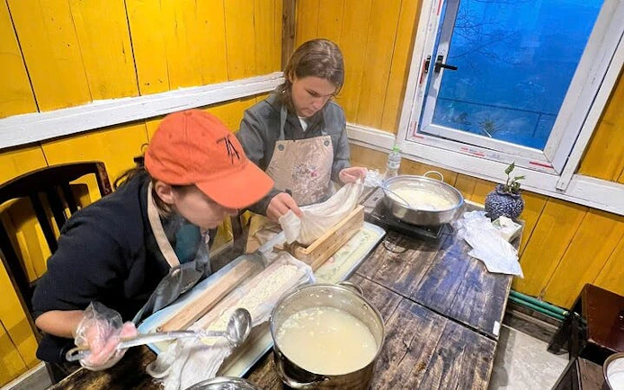Two people making tofu in a Sa Pa cooking class using traditional Vietnamese methods.