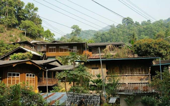 Mae Kham Pong Village traditional wooden houses surrounded by lush greenery, Chiang Mai.