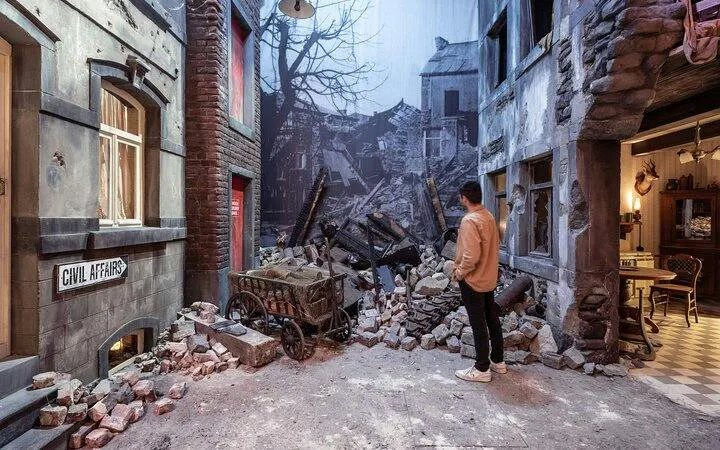 Man observing World War II ruins exhibit at Bastogne War Museum, part of Battle of the Bulge tour.
