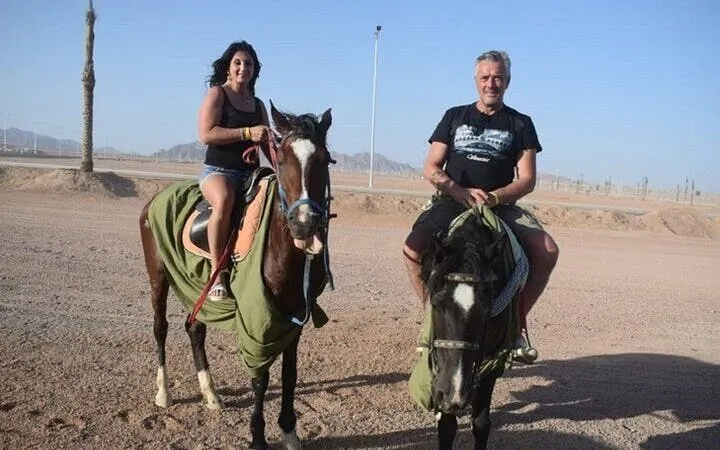 Horseback riders in the desert near Hurghada, Egypt, with distant mountains.