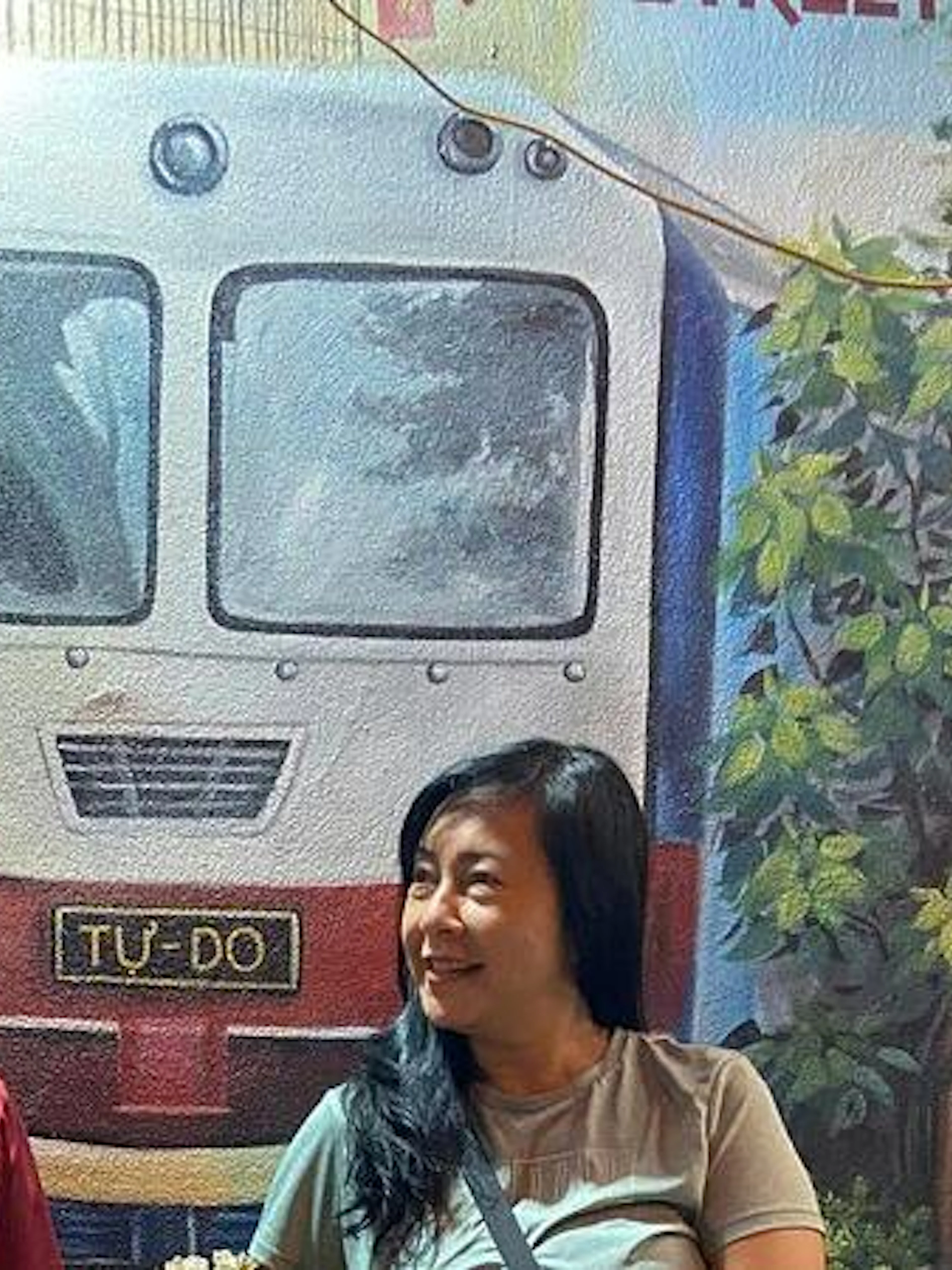 Couple enjoying Hanoi nightlife with train mural backdrop.