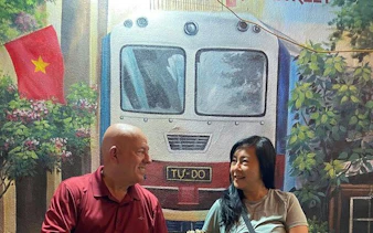 Couple enjoying Hanoi nightlife with train mural backdrop.