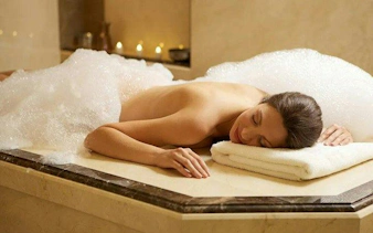 Person relaxing on a marble slab during a Turkish bath with foam, Alanya Hamam.