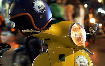 Yellow Vespa with helmet on Hanoi street, capturing night tour ambiance.