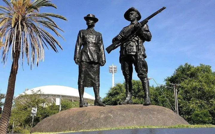 Statues of soldiers in Adelaide park with stadium in background.