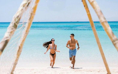 Couple running on a sandy beach during a private speedboat trip to Hula Hula Island, Hurghada.