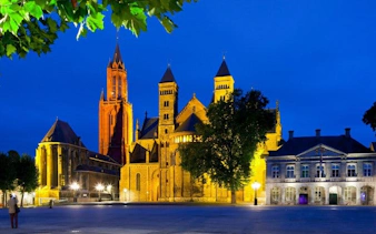 Maastricht's Basilica of Saint Servatius illuminated at night during self-guided walking tour.