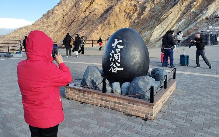 Person photographing the Owakudani black egg monument in Hakone, Japan.