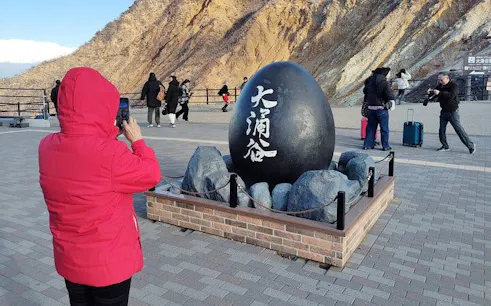 Person photographing the Owakudani black egg monument in Hakone, Japan.
