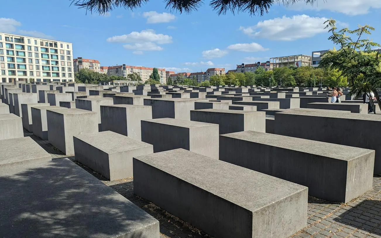 Holocaust Memorial in Berlin with concrete slabs under a blue sky.