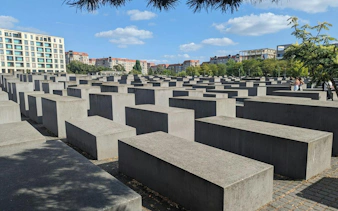 Holocaust Memorial in Berlin with concrete slabs under a blue sky.