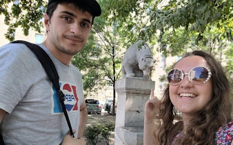 Visitors exploring Buda Castle District with a stone bear statue in the background.