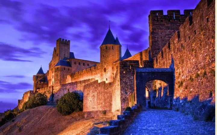 Carcassonne medieval fortress illuminated at dusk during self-guided walking tour.