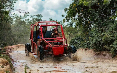 Buggy driving through muddy trail in Punta Cana jungle during Taino Park adventure.