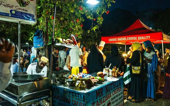 Stone Town Zanzibar night food market with people exploring local street food stalls.