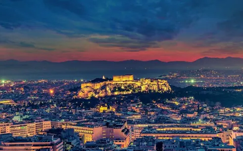 Acropolis of Athens illuminated at sunset, view from above the city.
