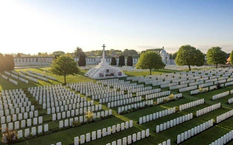 Flanders Fields cemetery with rows of white gravestones and central memorial cross, Belgium.