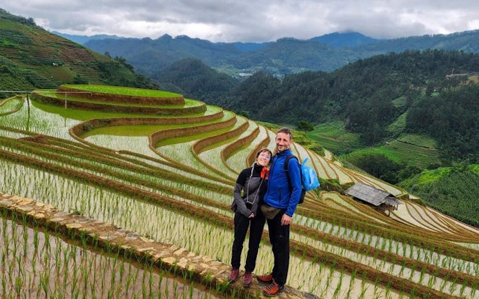 Couple standing on Mu Cang Chai rice terraces during trekking tour in Vietnam.