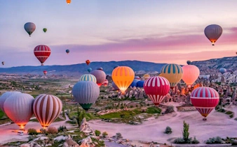 Hot air balloons over Cappadocia landscape at sunrise, Turkey.