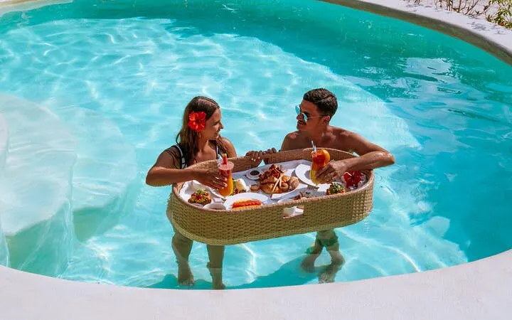 Couple enjoying floating breakfast in pool, Zanzibar Escape tour.