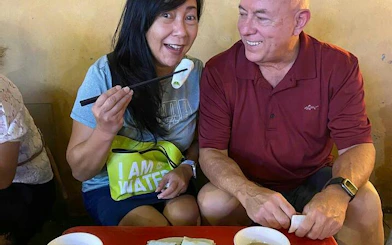 Tourists enjoying street food during Hanoi City Motorbike Tour, sampling local dishes.