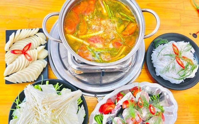 Traditional hotpot meal with fresh vegetables and herbs in Sapa, Vietnam.