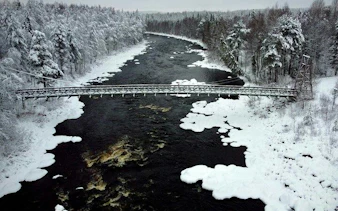 Bridge over snowy river in Vikakongas Nature Reserve, Rovaniemi.