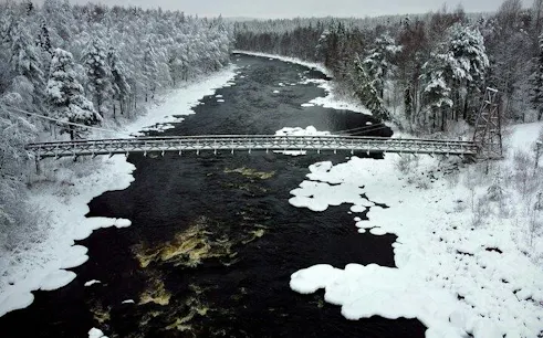 Bridge over snowy river in Vikakongas Nature Reserve, Rovaniemi.