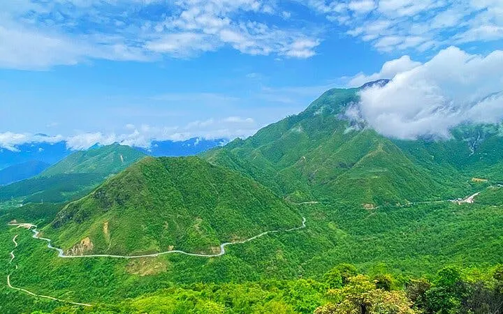 Mountainous landscape in Sapa with winding roads and lush greenery under a cloudy sky.