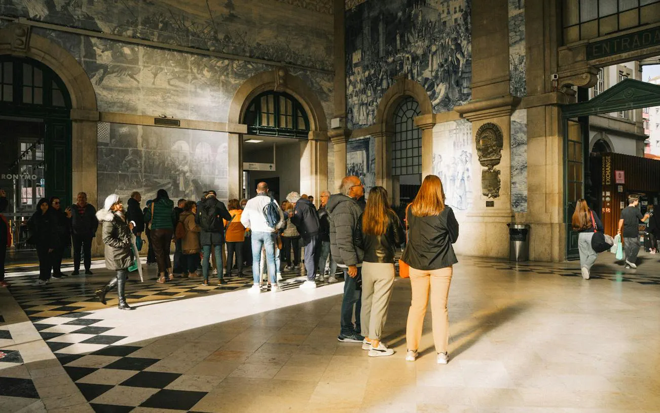 Visitors inside São Bento Railway Station, Porto, viewing historic azulejo tile murals.