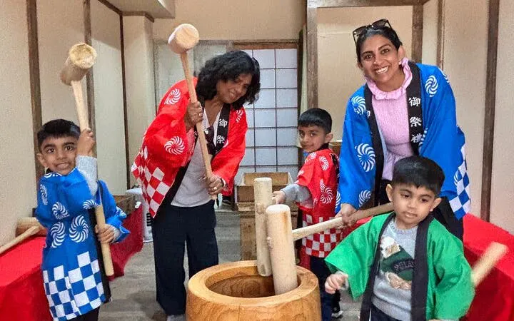 Traditional mochi pounding experience with participants in colorful costumes using wooden mallets.