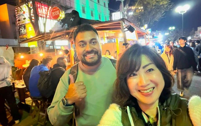 Nakasu food stall tour in Fukuoka with people enjoying street food at night.