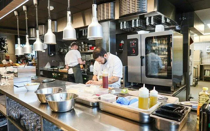 Chefs preparing traditional Norwegian meal in Oslo kitchen during walking tour.