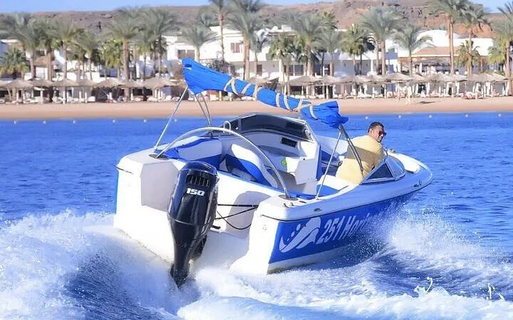 Speedboat cruising along Sharm El Sheikh shoreline with palm trees and beach in background.