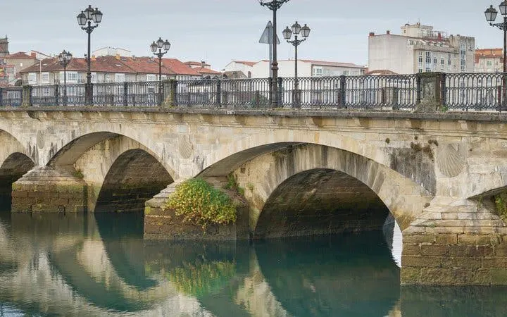 Pontevedra stone bridge over calm river on self-guided walking tour route.
