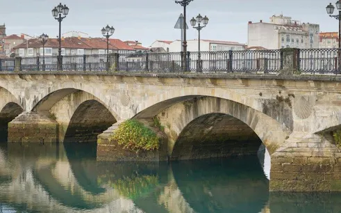 Pontevedra stone bridge over calm river on self-guided walking tour route.