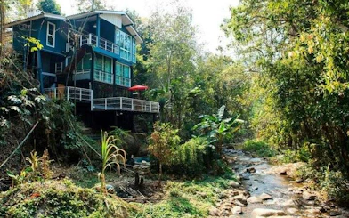 Mae Kham Pong Village house by a stream surrounded by lush greenery, Chiang Mai.