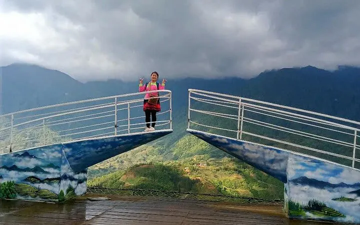 Person standing on Sa Pa glass bridge with scenic mountain view in background.